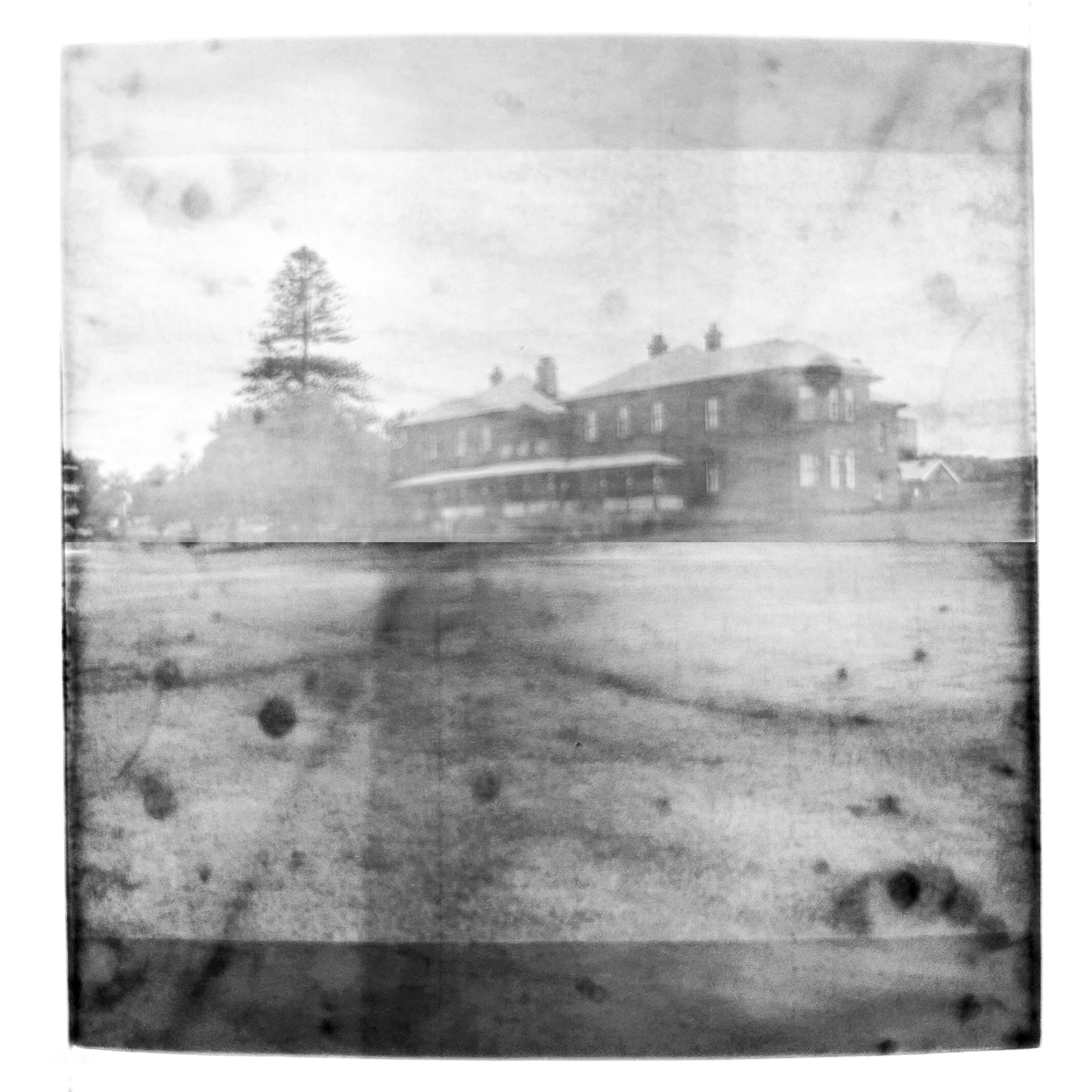 A black and white double exposure photograph of the La Perouse Cable Station overlayed with an image of the landscape surrounding the building