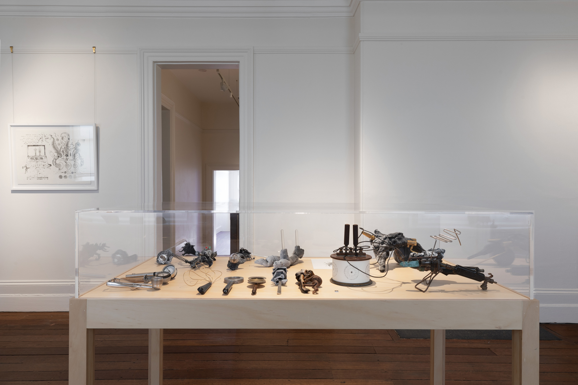 A pine museum plinths holds objects that look like old phones and gizmo's from a bygone era of telecommunications by the artist Jack Stahel