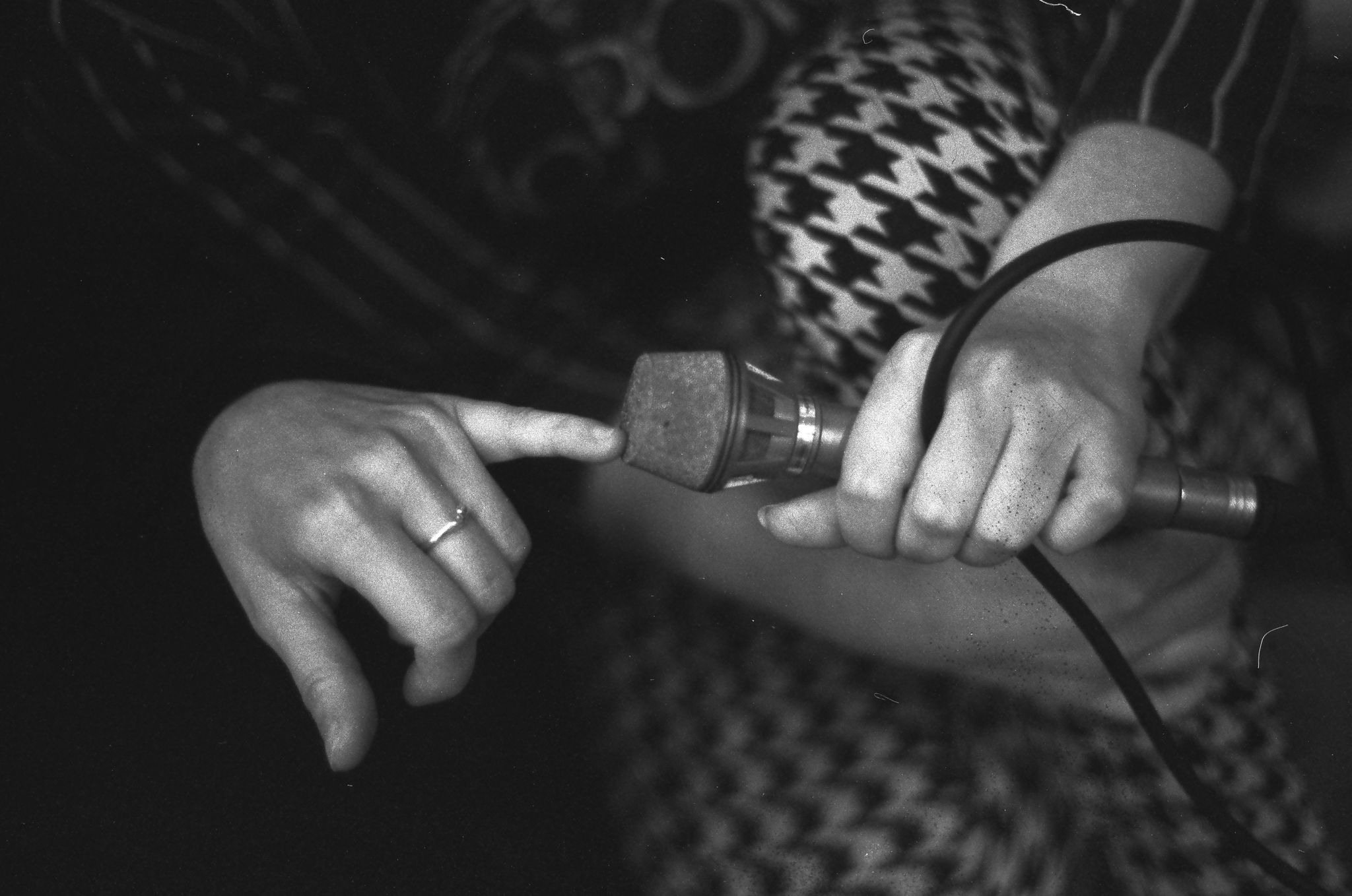 A human hand touches the top of a microphone - the hand belongs to a member of the sound collective CIRCUL who are performing at La Perouse Macquarie Watchtower